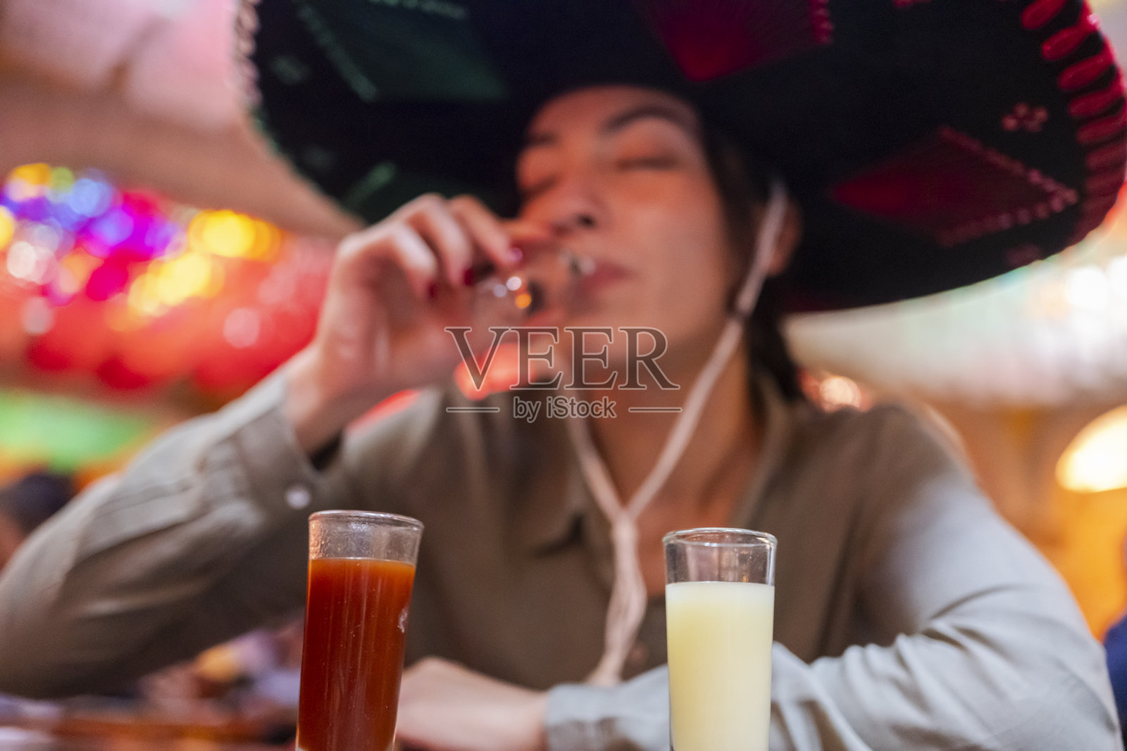 一位年轻游客在墨西哥全国性节日期间品尝各种龙舌兰酒，头戴一顶传统的查罗帽。照片摄影图片