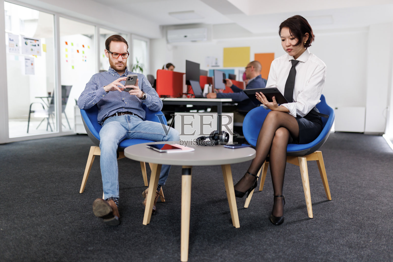 现代办公室商务会议，专业人士正在讨论并使用数字设备。照片摄影图片