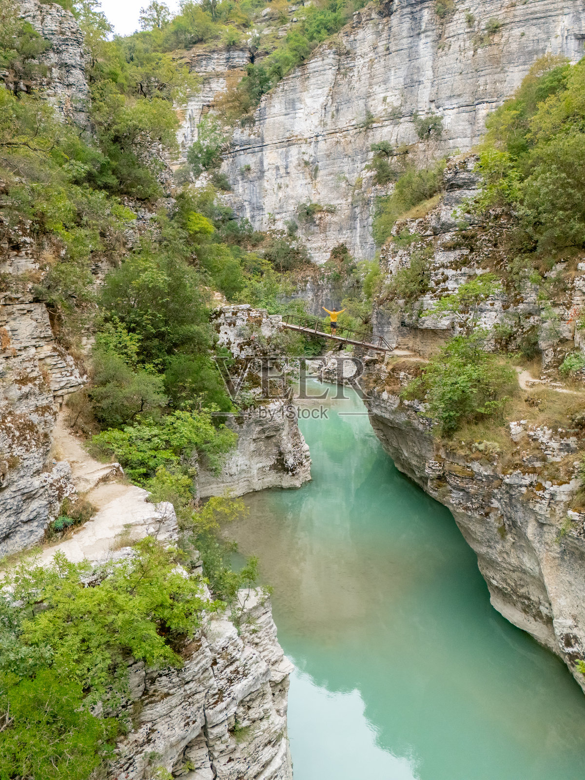 男人站在峡谷河流上的狭窄桥梁上照片摄影图片
