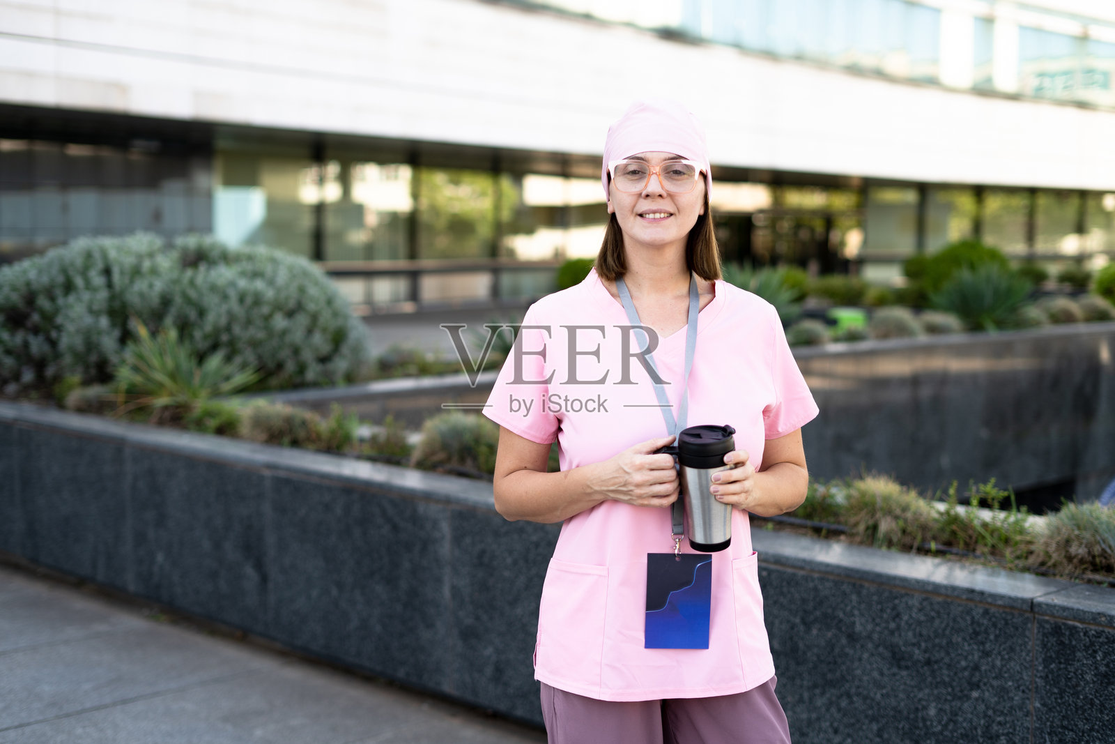 一位女医生在户外站着，手里拿着咖啡杯。照片摄影图片