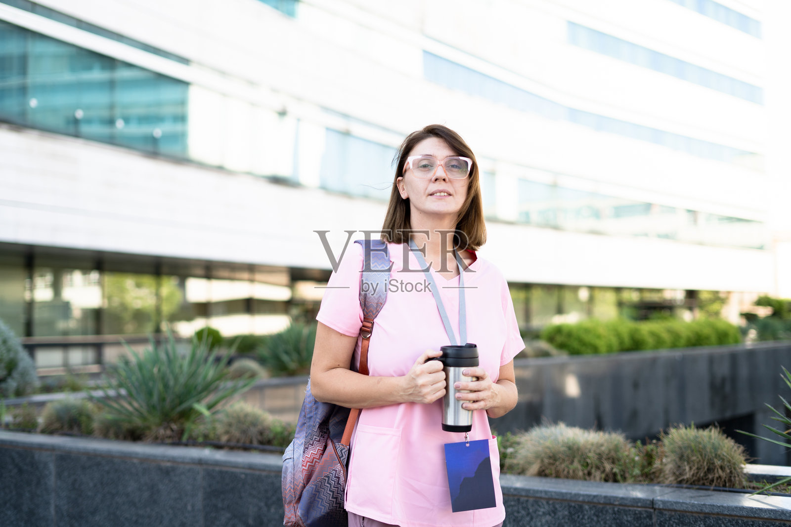 一名女医生站在户外，手里拿着咖啡杯。照片摄影图片