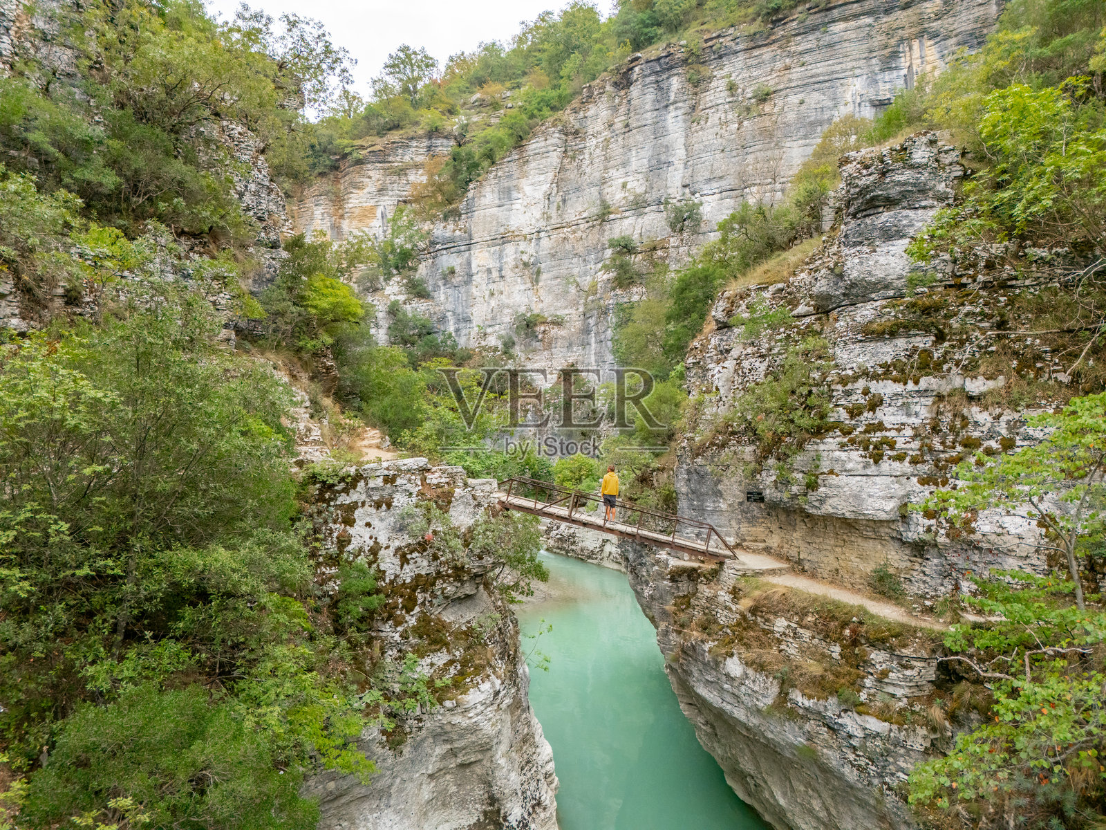 人行横跨峡谷河流上的狭窄桥梁照片摄影图片