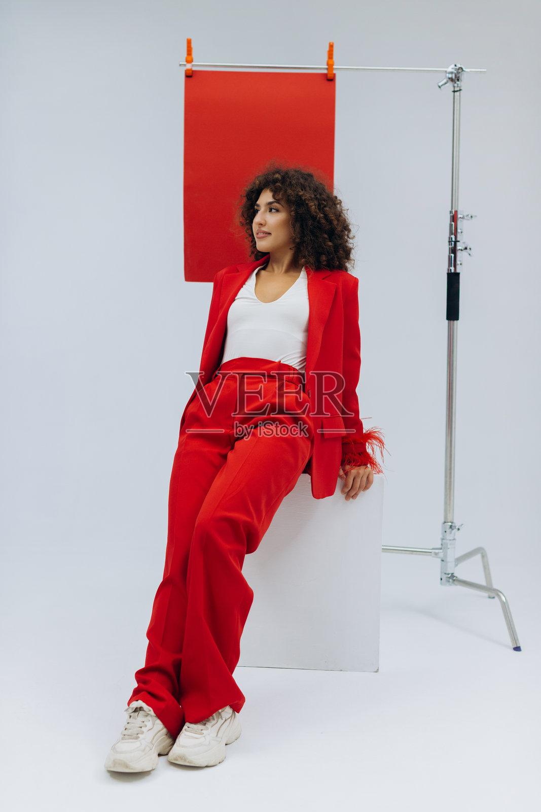 身穿红色套装的时尚卷发女子正在摆姿势照片摄影图片