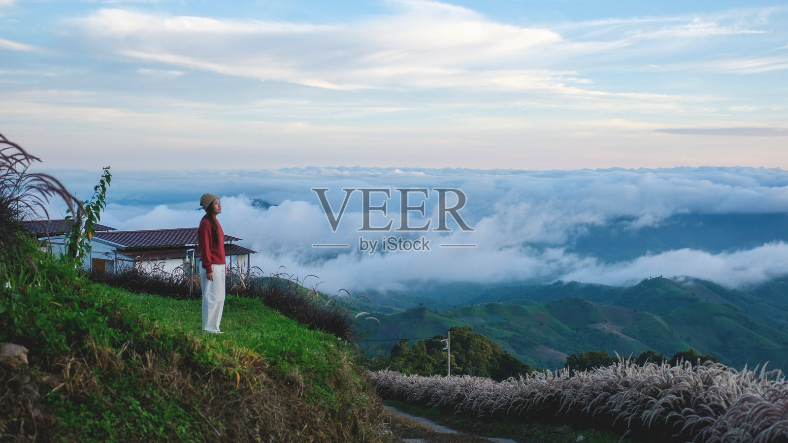 雾气弥漫的早晨，一位女士站着眺望山景。照片摄影图片