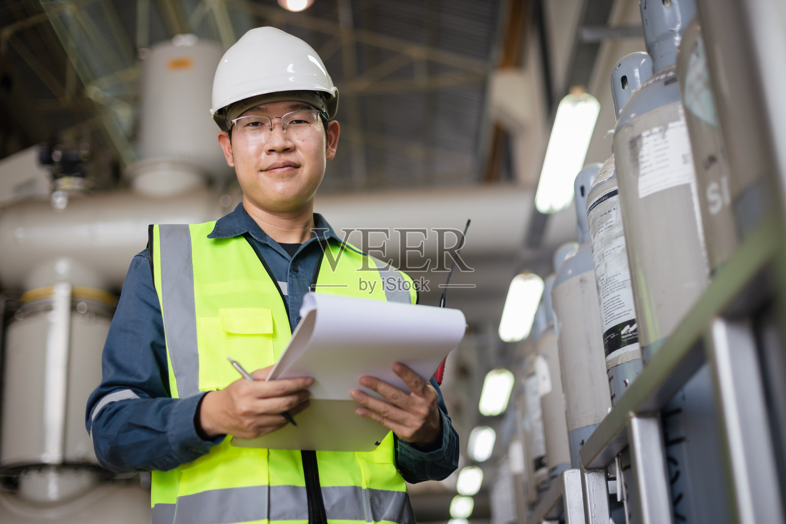 工业设施内工程师检查六氟化硫气瓶。重点关注安全、压力容器检查、危险品管理和工作场所安全清单记录。照片摄影图片