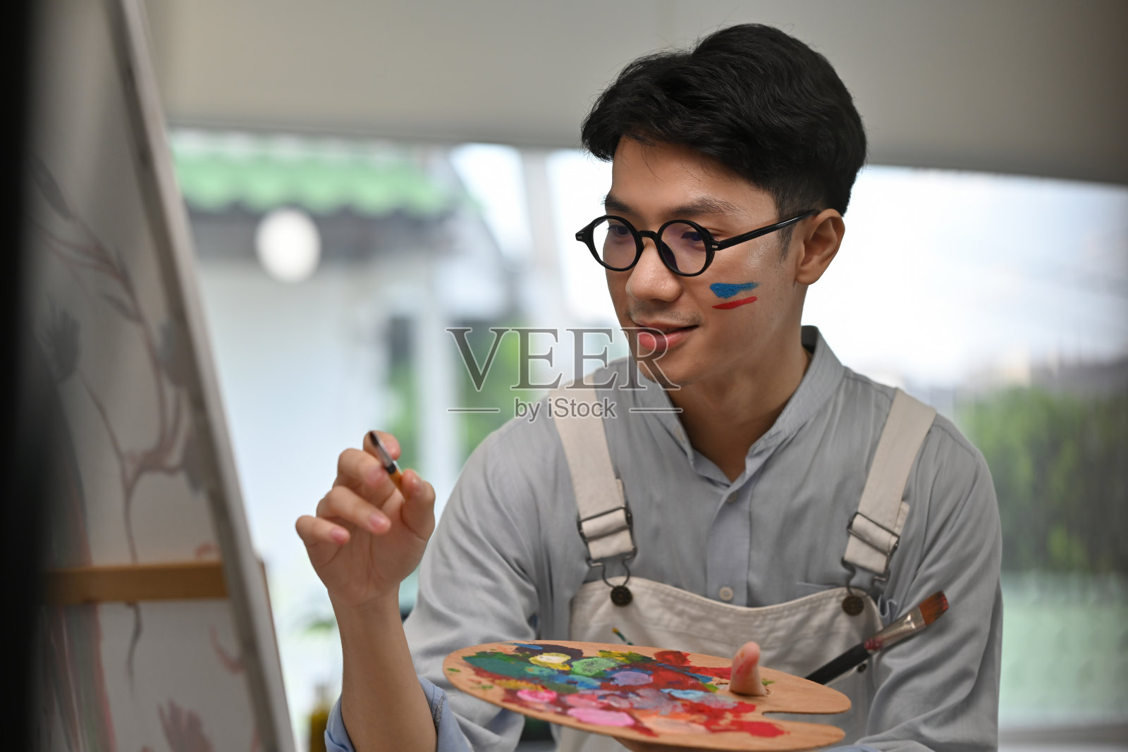 专注的年轻画家正用稳健的双手和鲜艳的色彩为他的艺术作品添加细节，尽情挥洒创意与喜悦。照片摄影图片