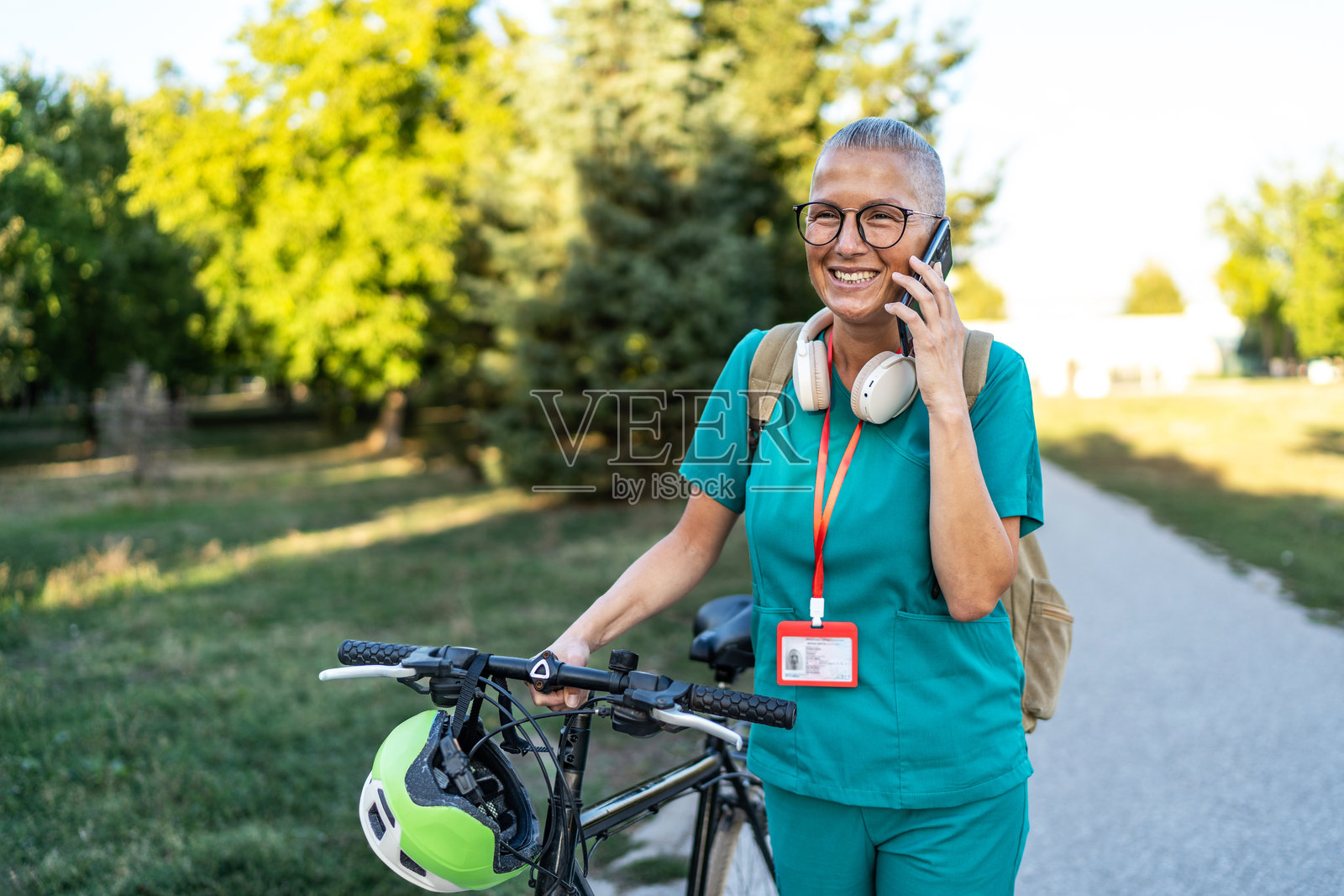 快乐的护士骑自行车通勤时正在打电话照片摄影图片