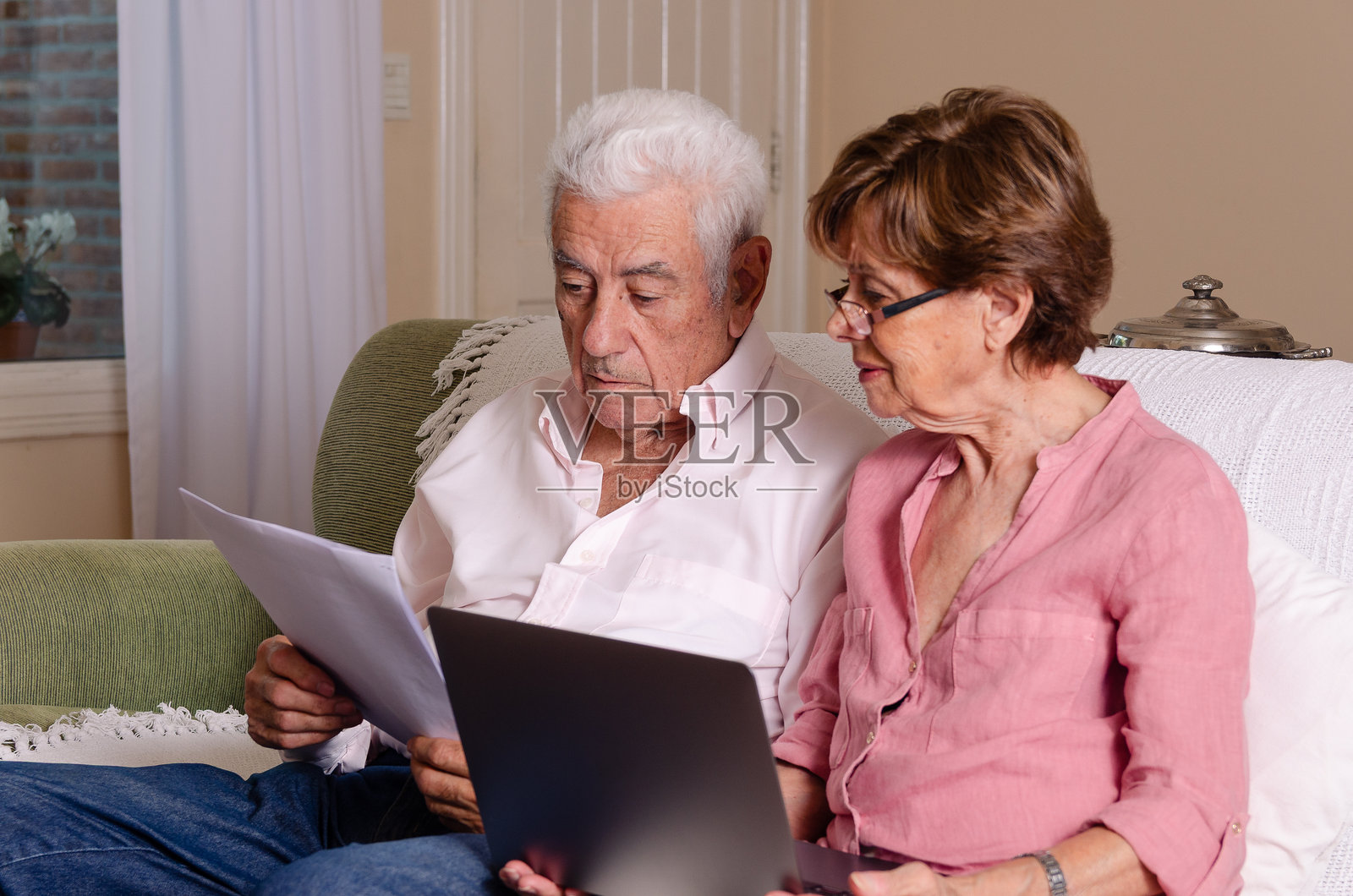 一对老年夫妇在家中使用笔记本电脑。照片摄影图片