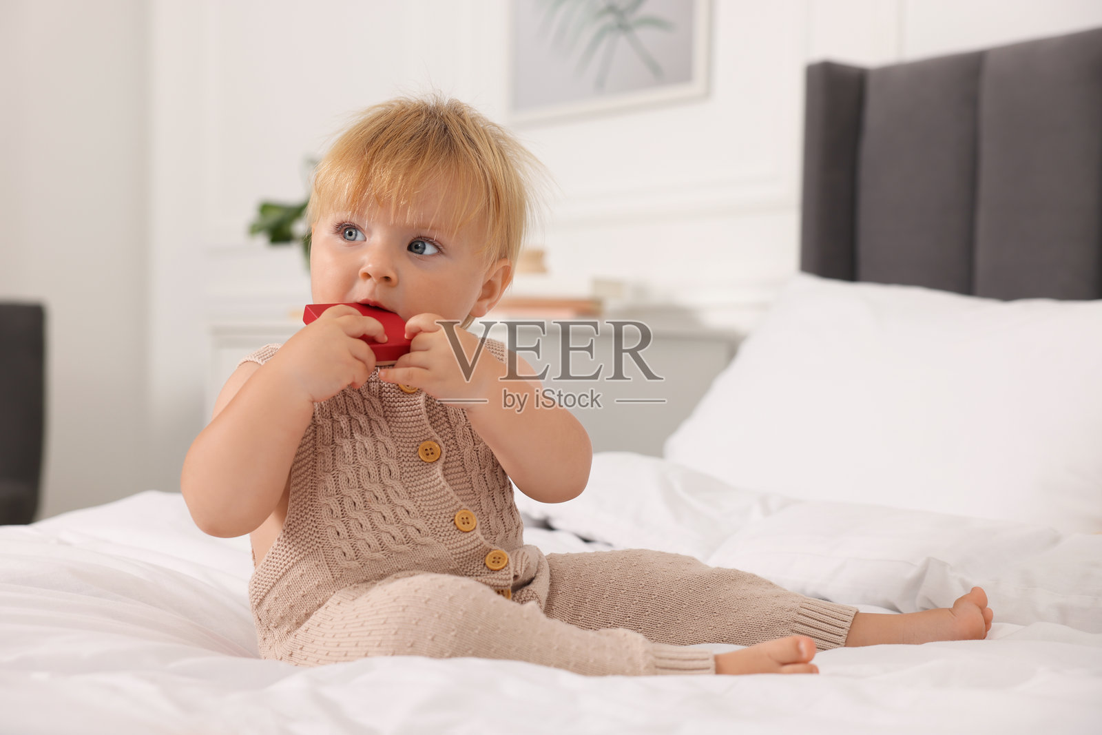 可爱的婴儿带着玩具坐在家里的床上照片摄影图片