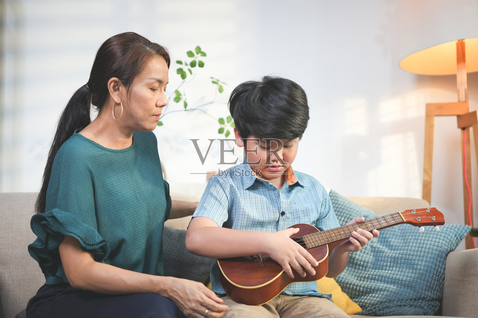 母子在家享受音乐，一家人弹吉他、拍手的乐趣，儿子为妈妈弹奏吉他照片摄影图片