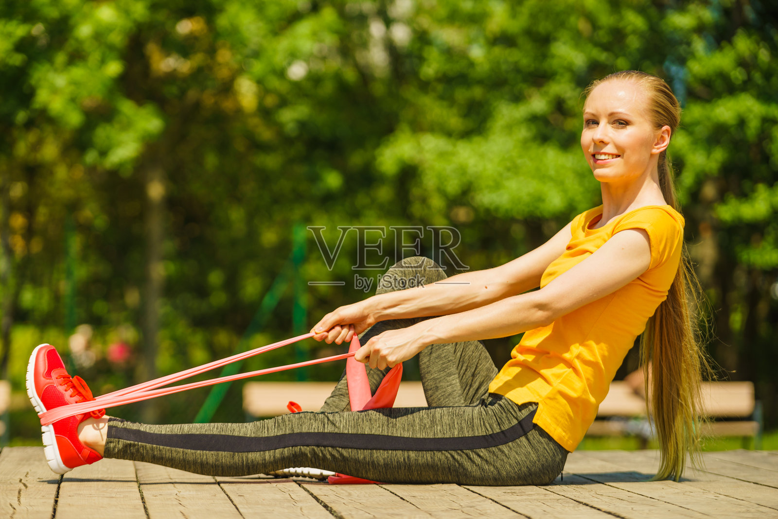 女孩在户外锻炼，使用弹力带。照片摄影图片