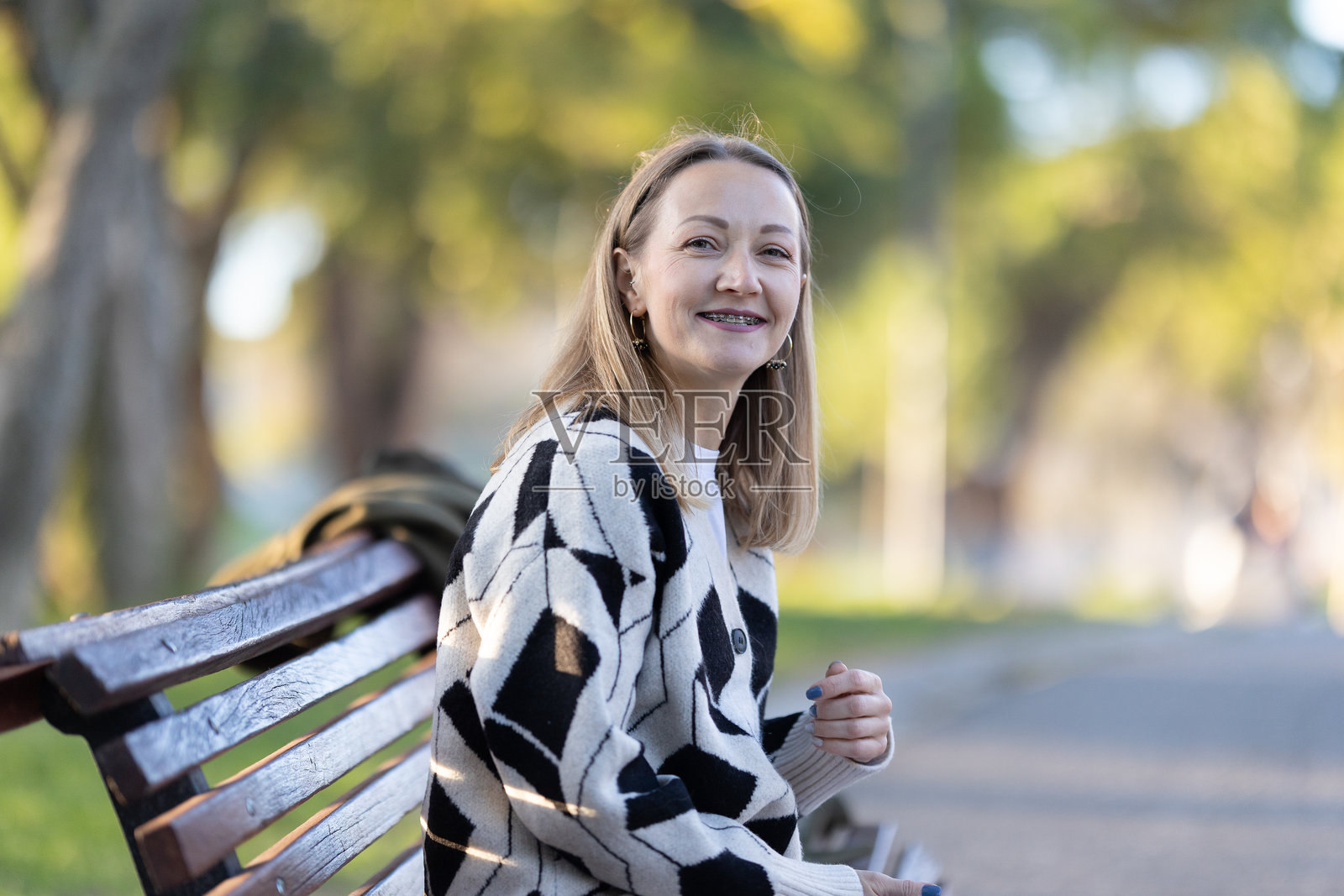 一名女子面带微笑坐在公园长椅上照片摄影图片