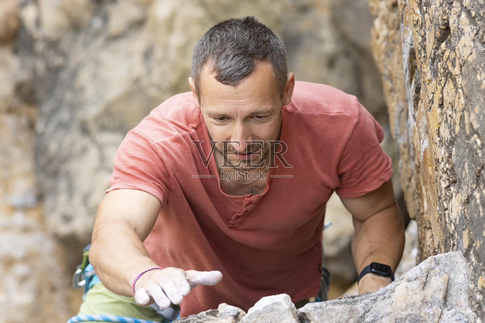 一名男性登山者在户外攀登岩壁，手沾满镁粉照片摄影图片