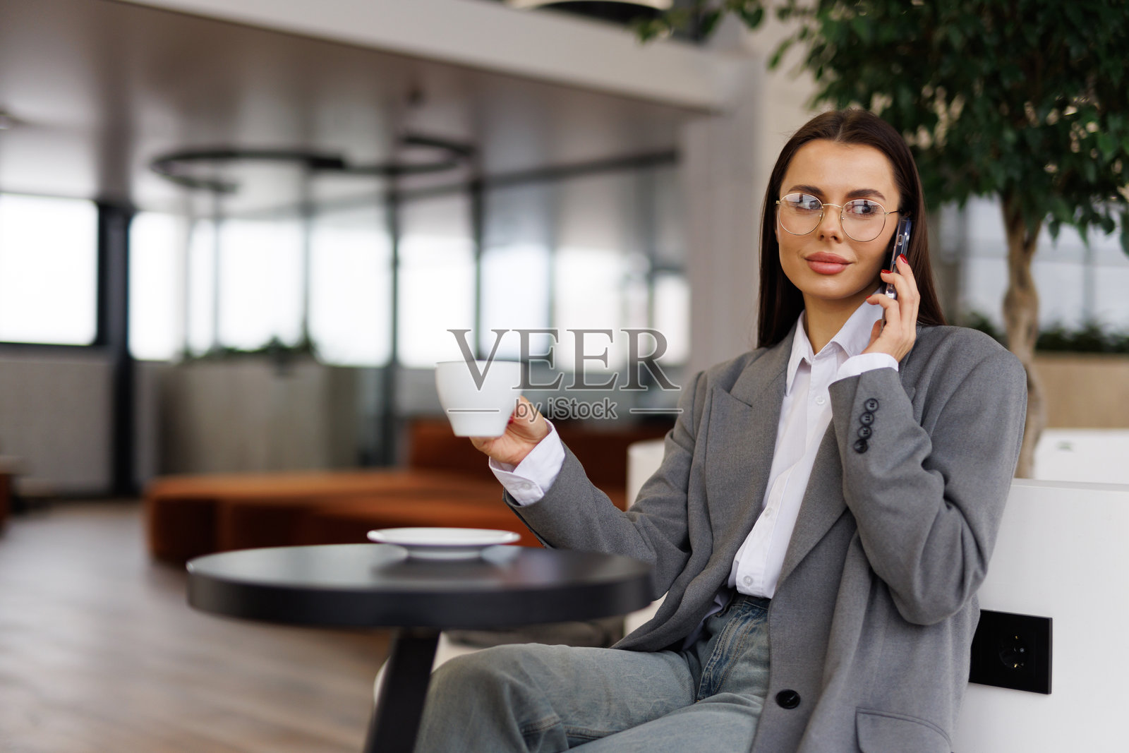 年轻迷人的女子在空闲时间独自坐在咖啡馆里，用手机打电话。照片摄影图片