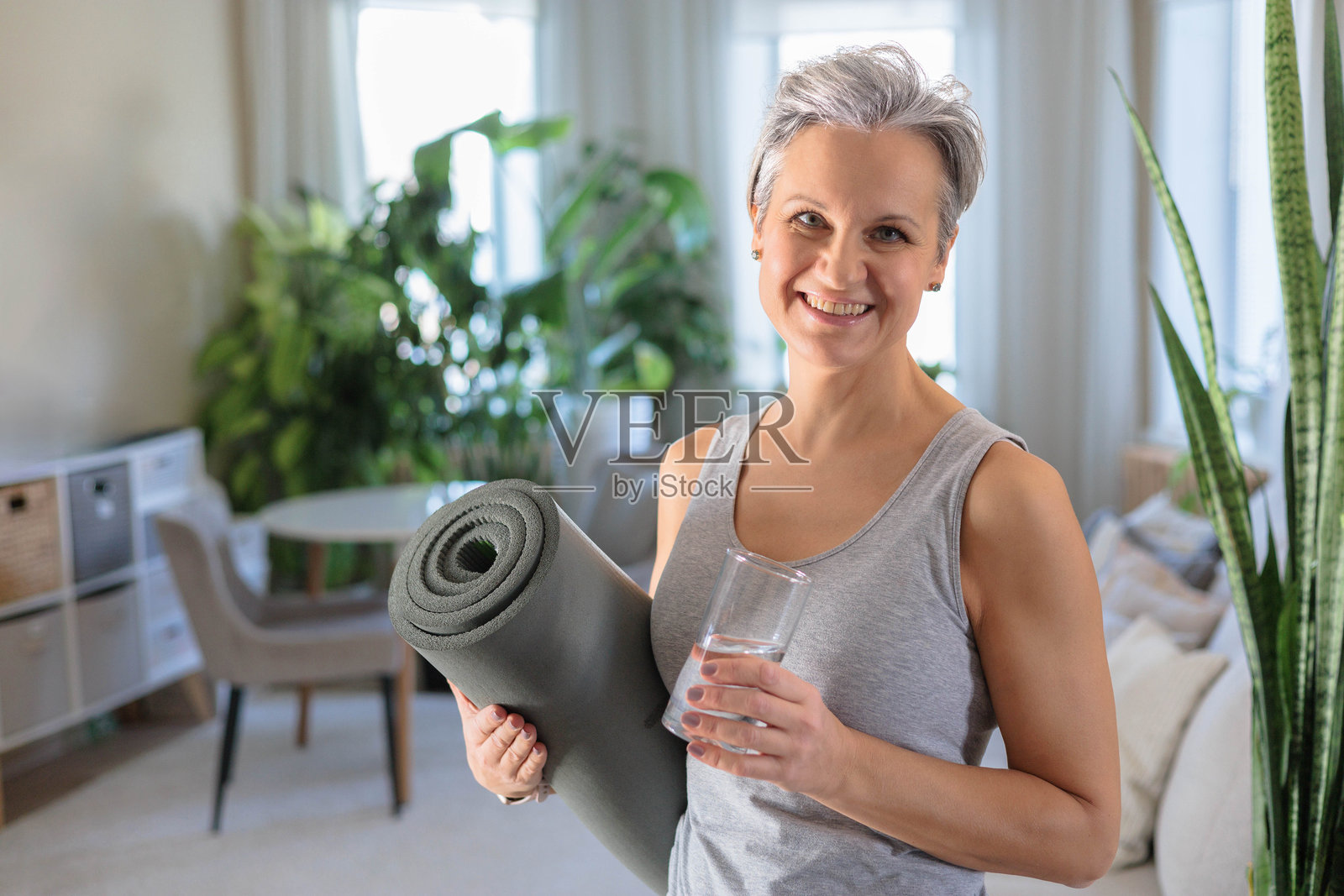 一位年长的白发女士微笑着，手中拿着一杯纯净饮用水照片摄影图片