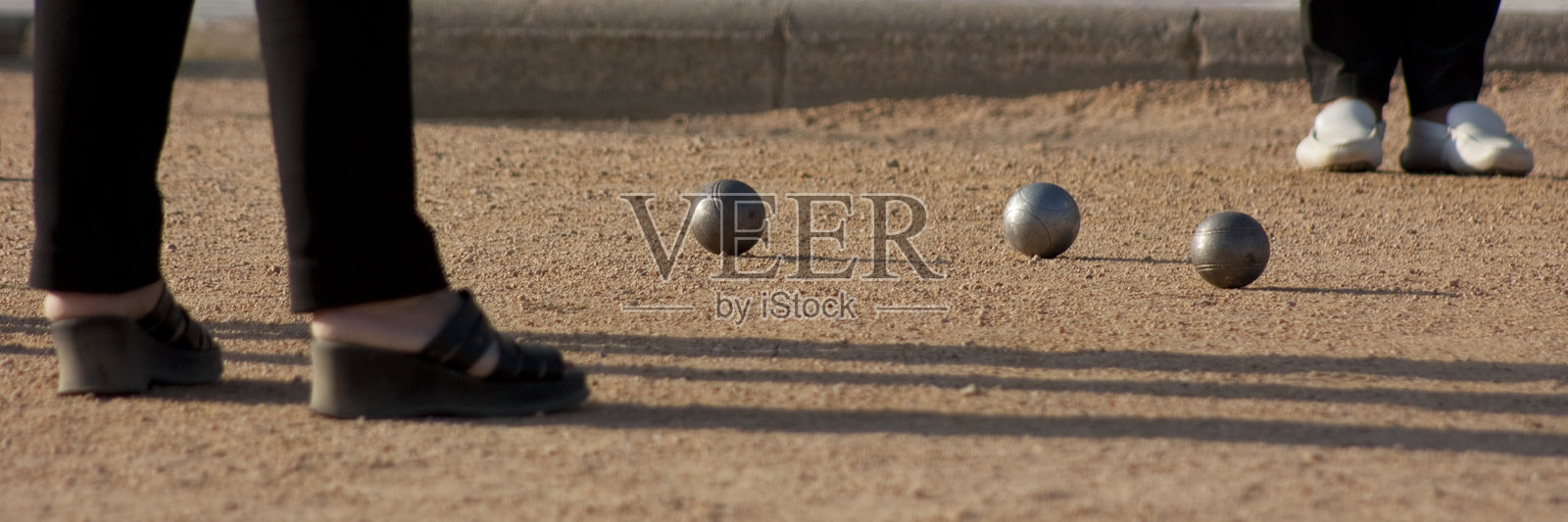 人们在沙地球场上玩滚球游戏，球是滚球（pétanque）照片摄影图片