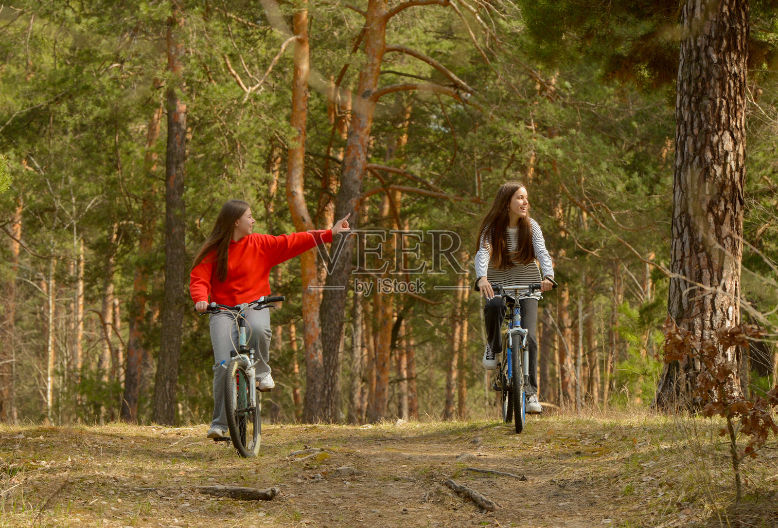 两个十几岁的女孩在森林里骑自行车照片摄影图片