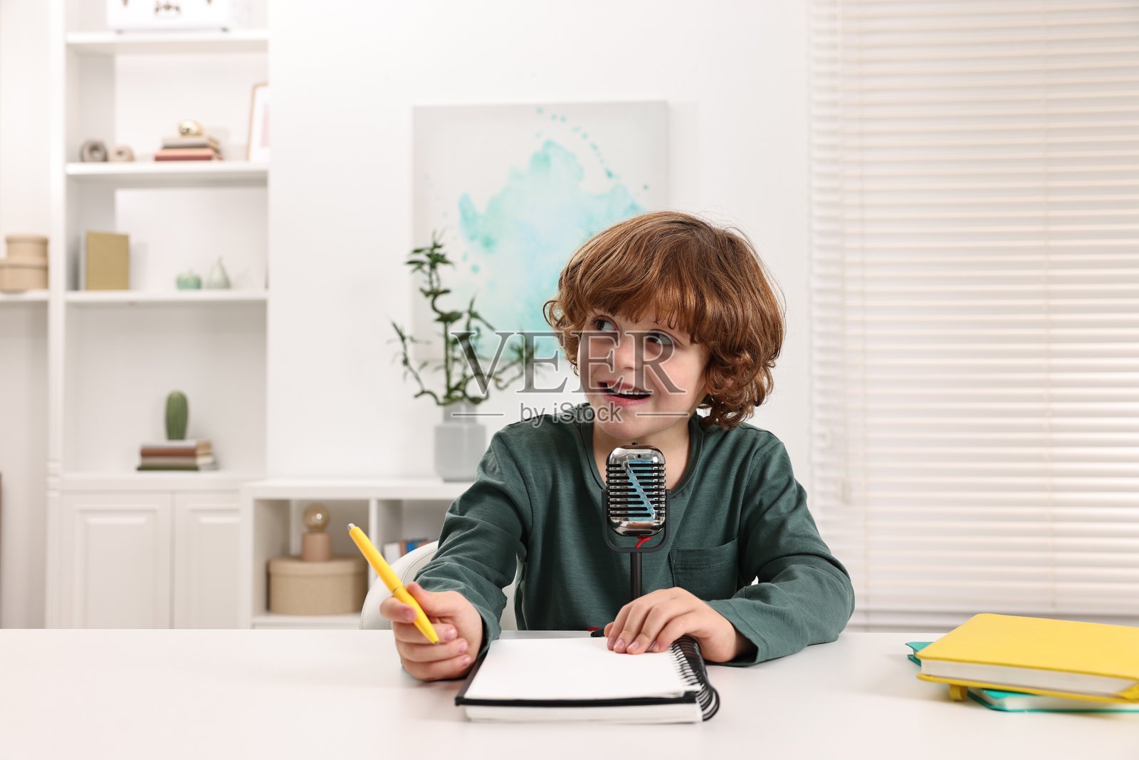 男孩在室内白色桌子旁拿着麦克风照片摄影图片