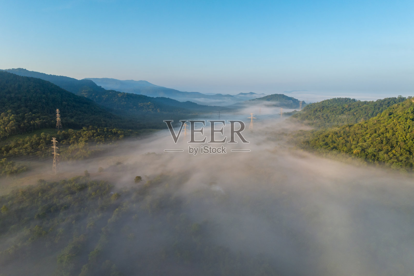 雾天山间绿化带景观，配有输电线路。森林、田野与高山、人造建筑、电缆。照片摄影图片