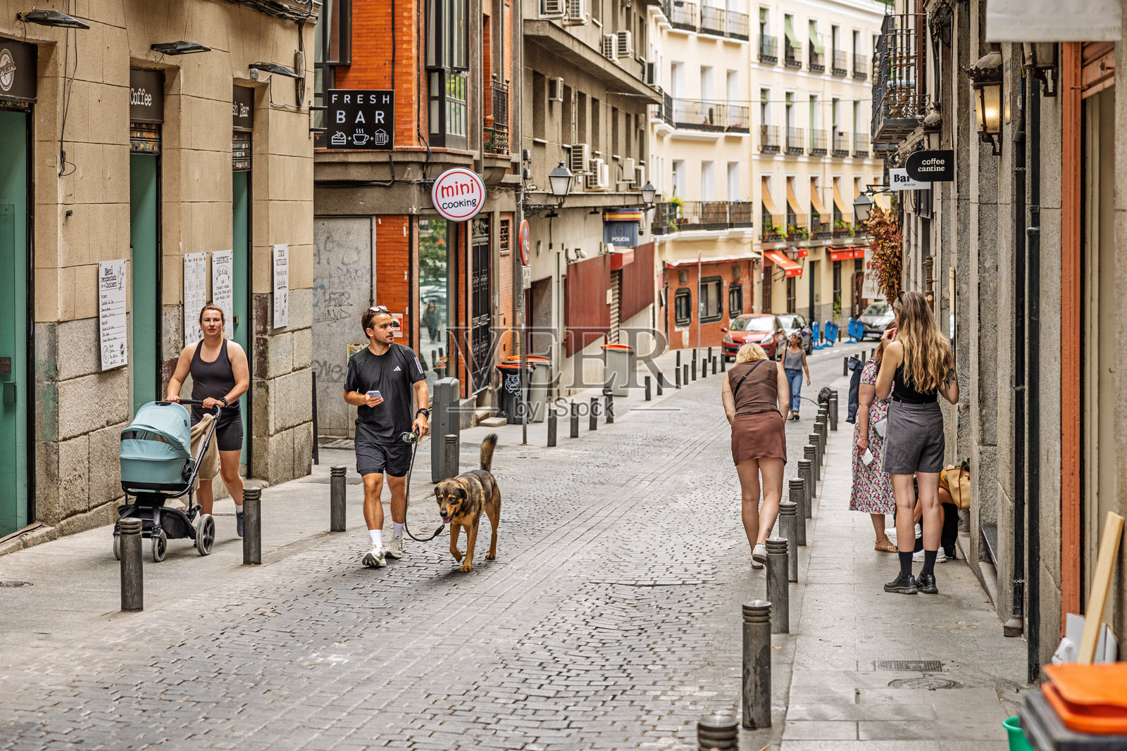 马德里市中心一条无车街道上,行人正在享受温暖的秋日午后。照片摄影图片