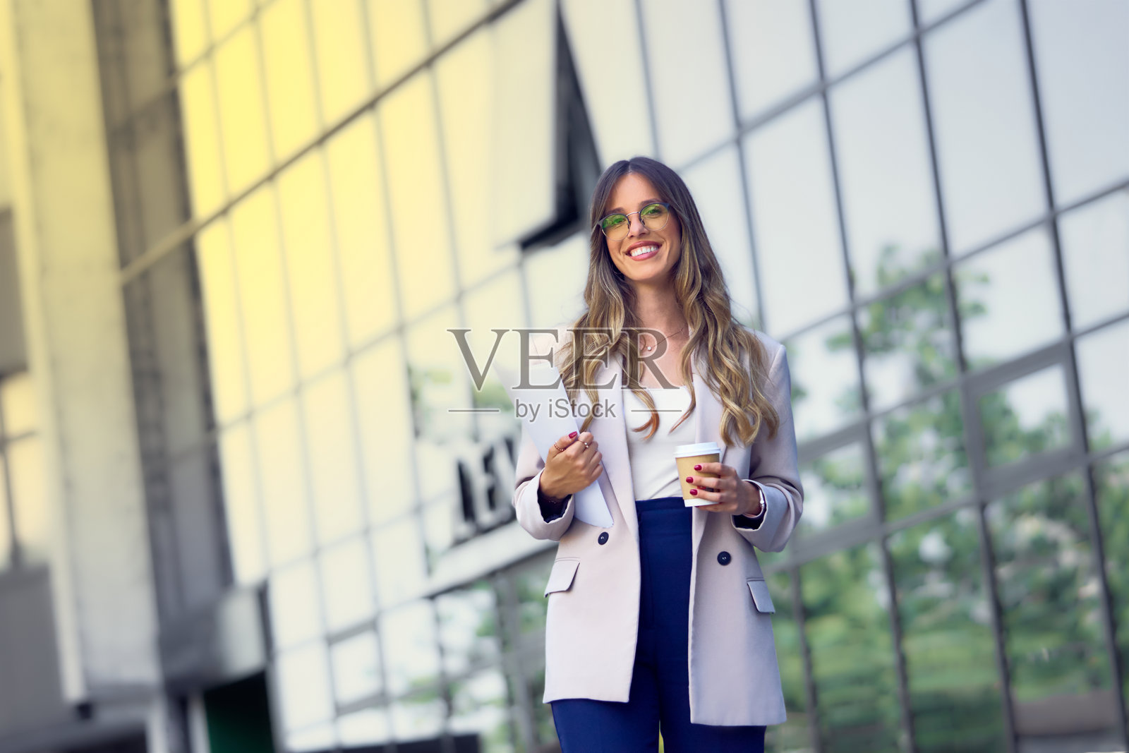 自信的年轻女商人面带微笑，身处城市之中照片摄影图片