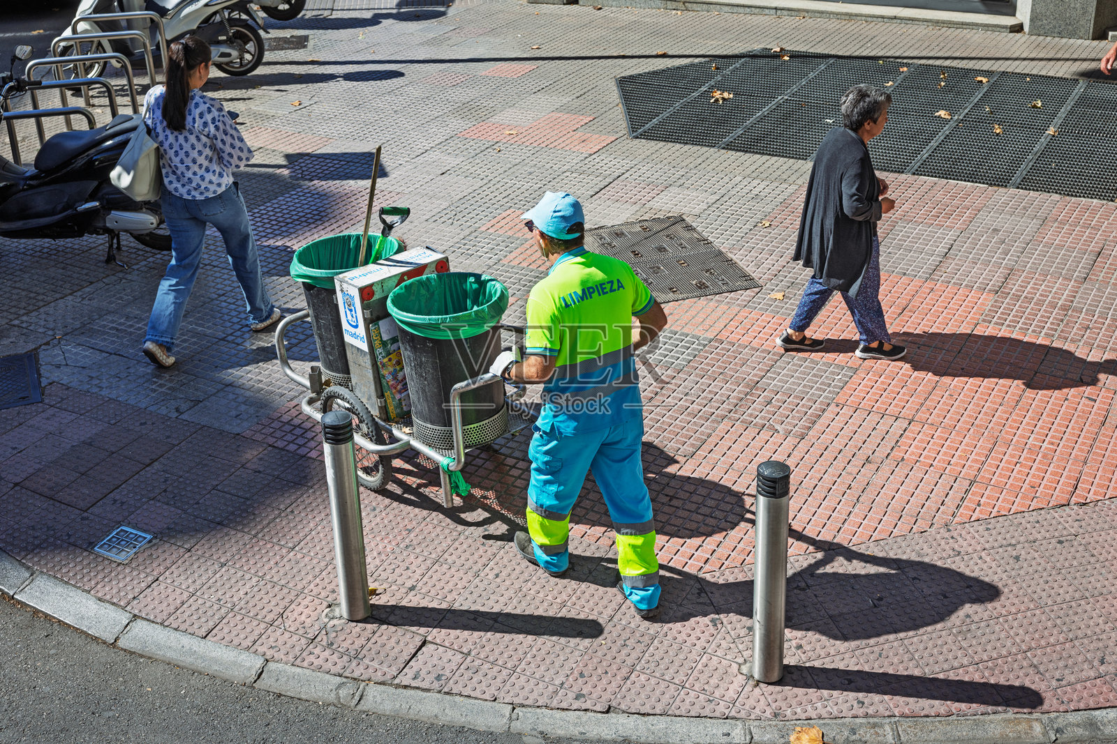 马德里地铁入口附近，一名男性清洁工推着垃圾车照片摄影图片