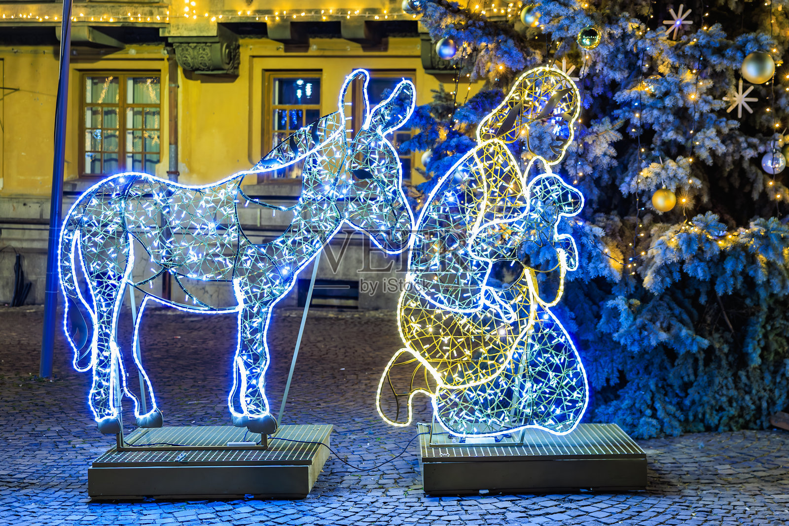 一个打扮成耶稣的男人坐在长椅上,旁边有一头驴。照片摄影图片