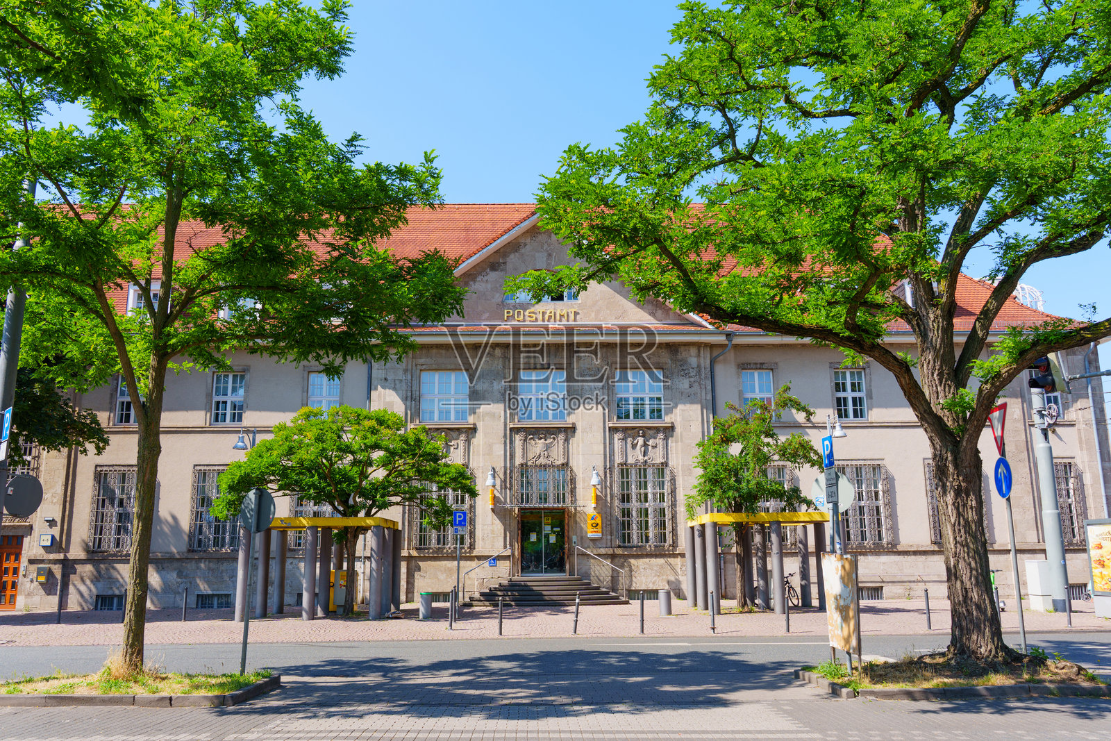 德国达姆施塔特历史邮局大楼，周围环绕着茂密的绿树。照片摄影图片