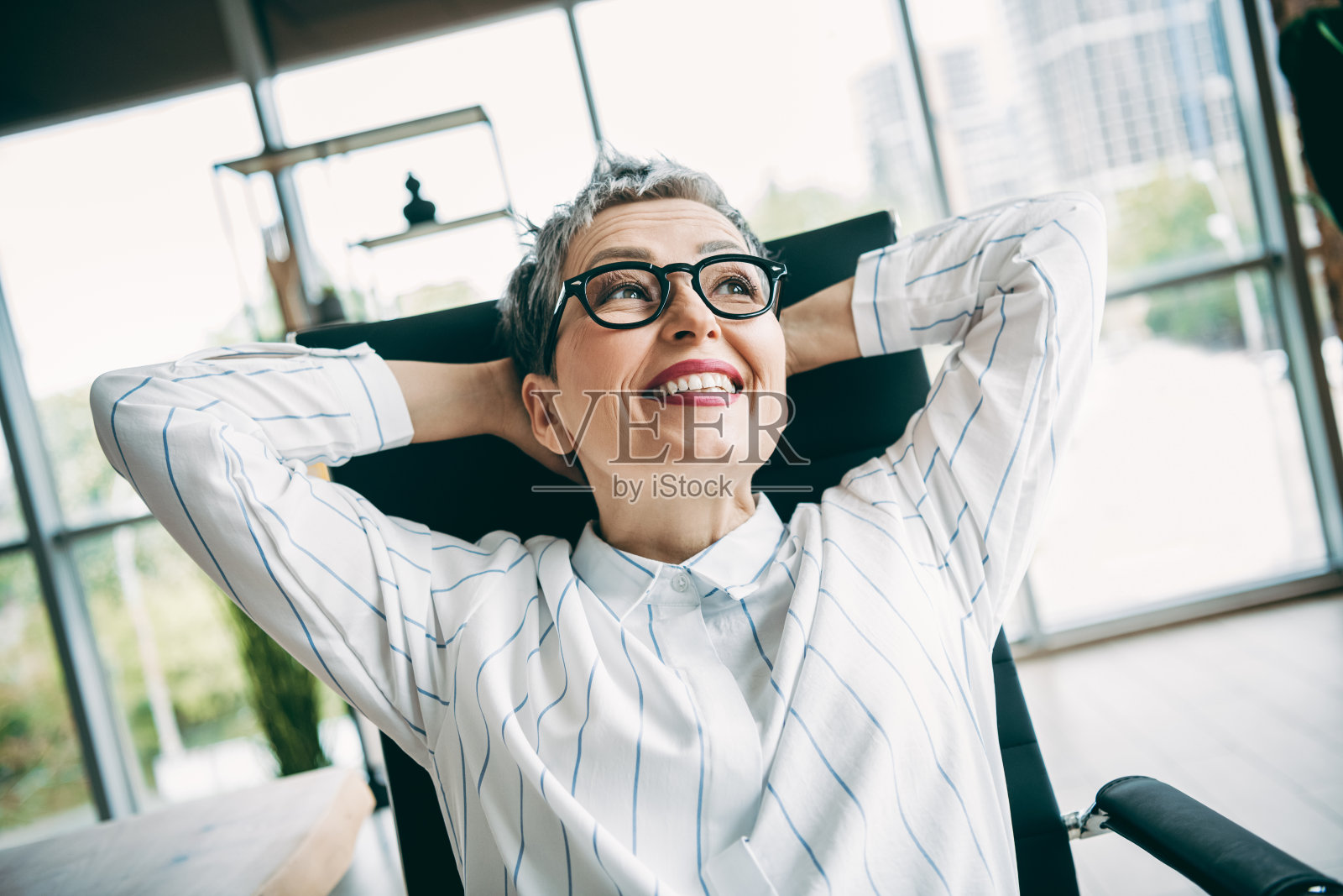 自信成熟的女商人在现代办公空间放松，享受职业成功和充满活力的工作环境照片摄影图片