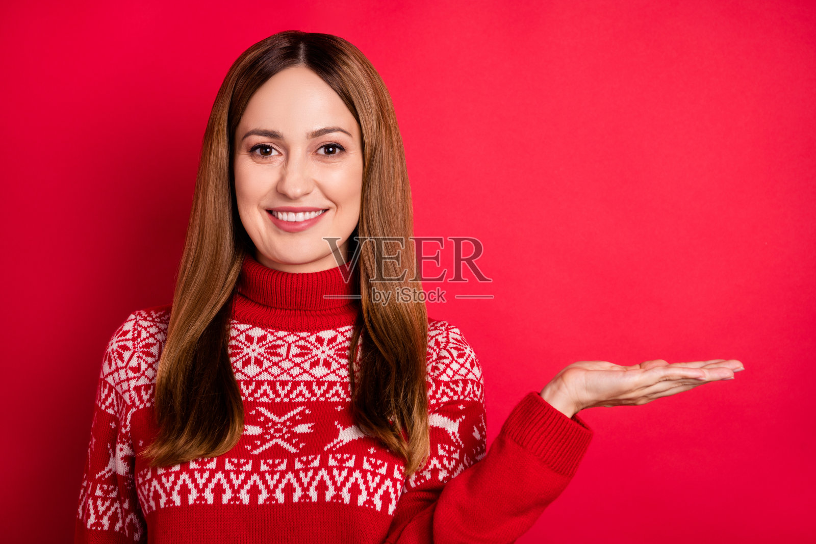 一位迷人的快乐女孩肖像，手掌托着空白的广告宣传空间，背景为鲜艳的红色照片摄影图片