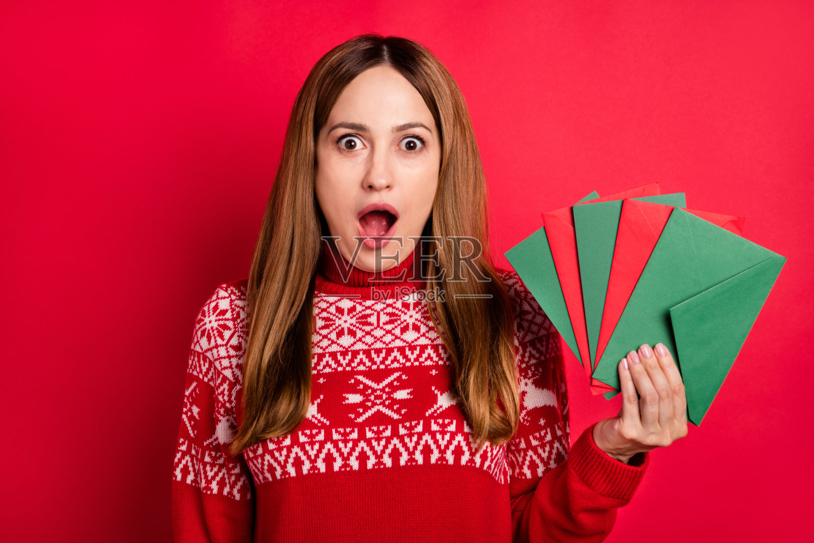 一位迷人的、快乐的、惊讶的女孩肖像，她手中拿着写有“十二月奇迹”的字母，背景是明亮的红色，孤立。照片摄影图片