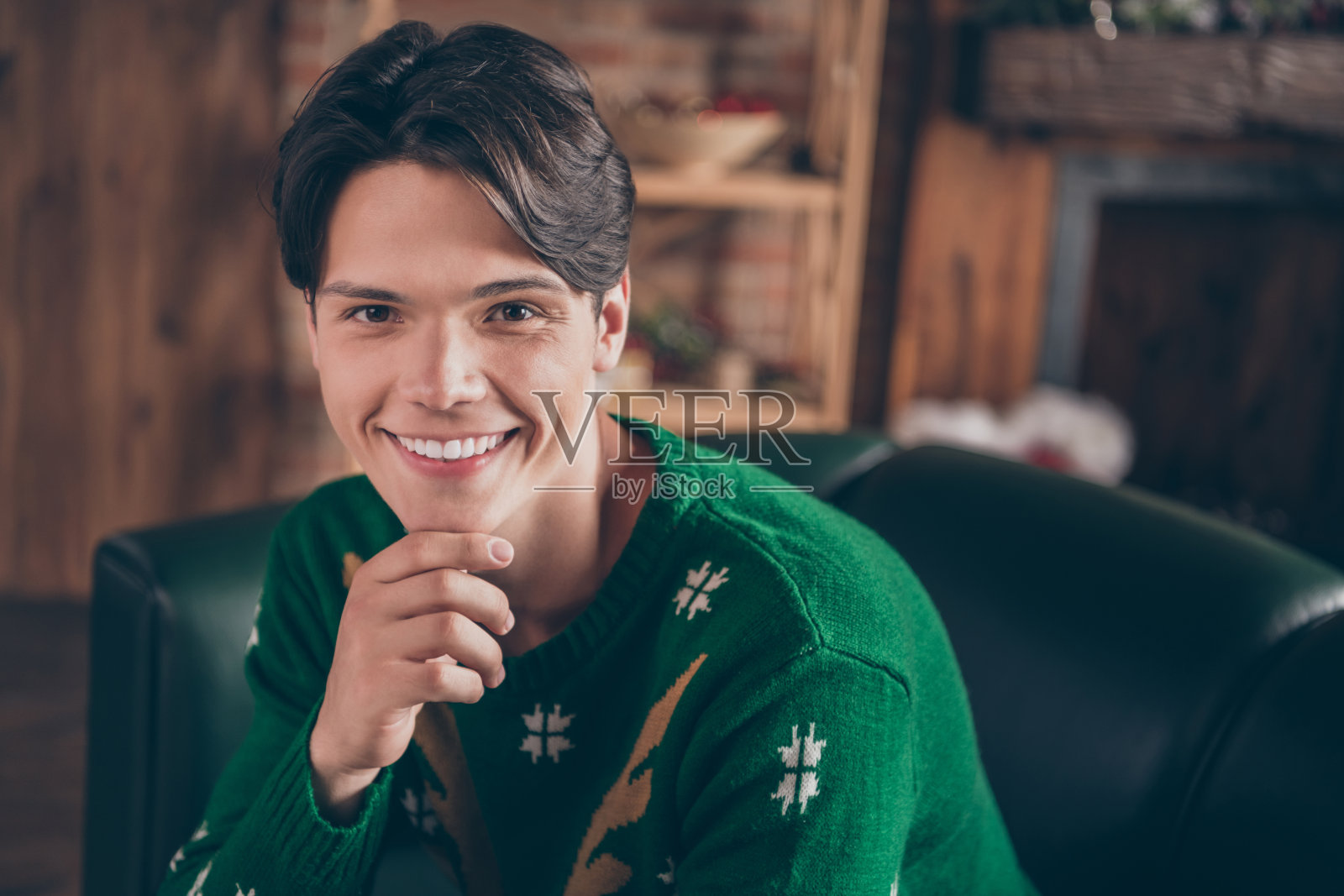 照片，一个迷人、快乐的年轻男子，手托下巴，面带微笑，心情愉悦，室内，圣诞节，房子，家，公寓照片摄影图片