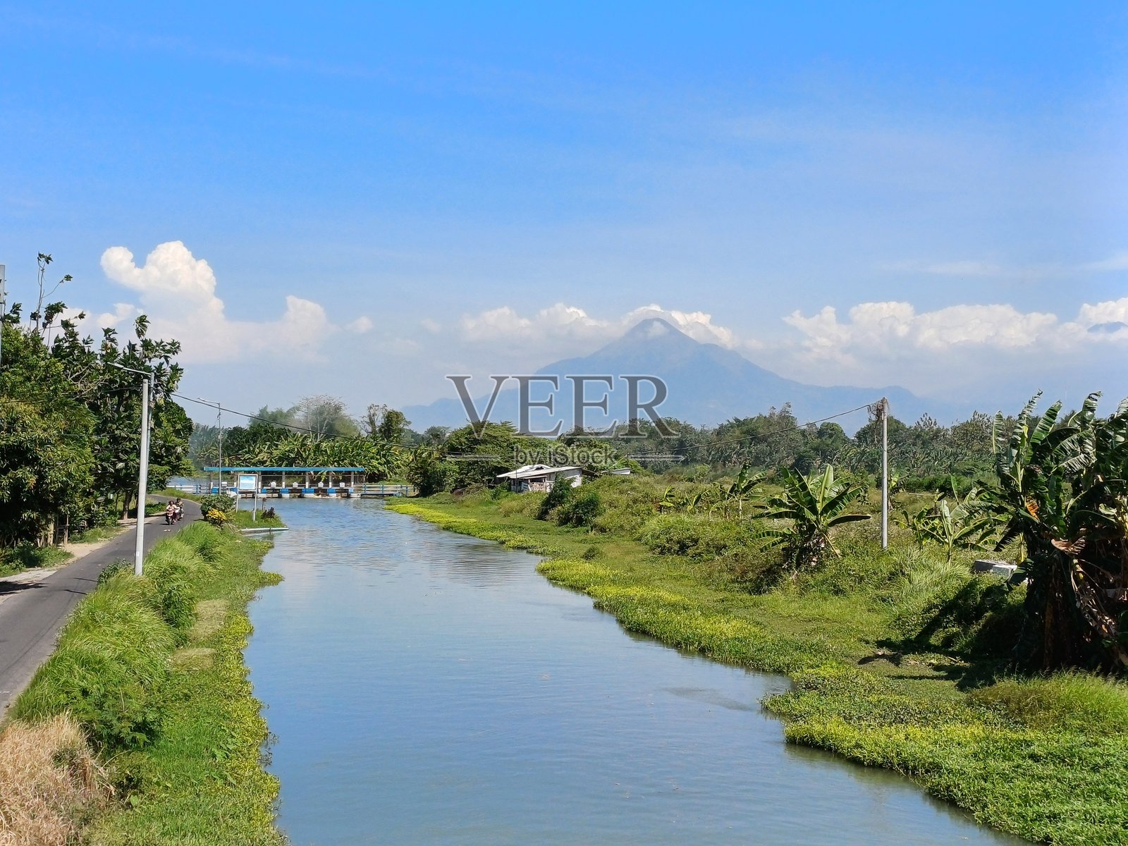 宁静的河流在绿色的田野和远处的山峦旁流淌照片摄影图片