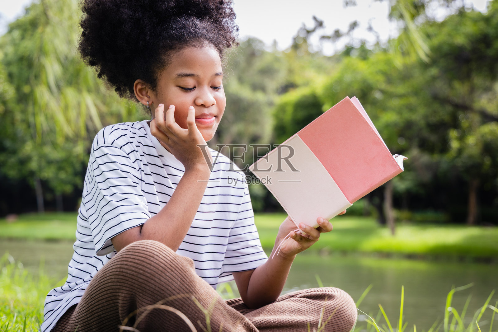 年轻女孩在公园里阅读，体现了家庭教育和宁静的生活方式照片摄影图片