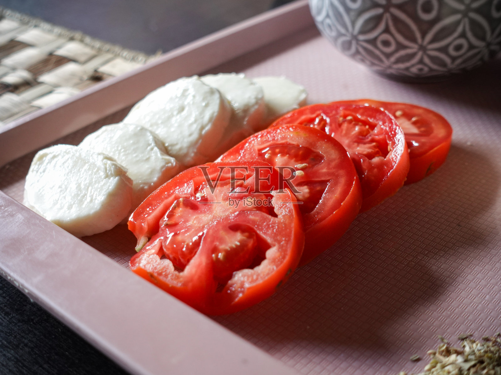两排：马苏里拉奶酪和新鲜番茄切片，食品盘角上撒有干牛至照片摄影图片