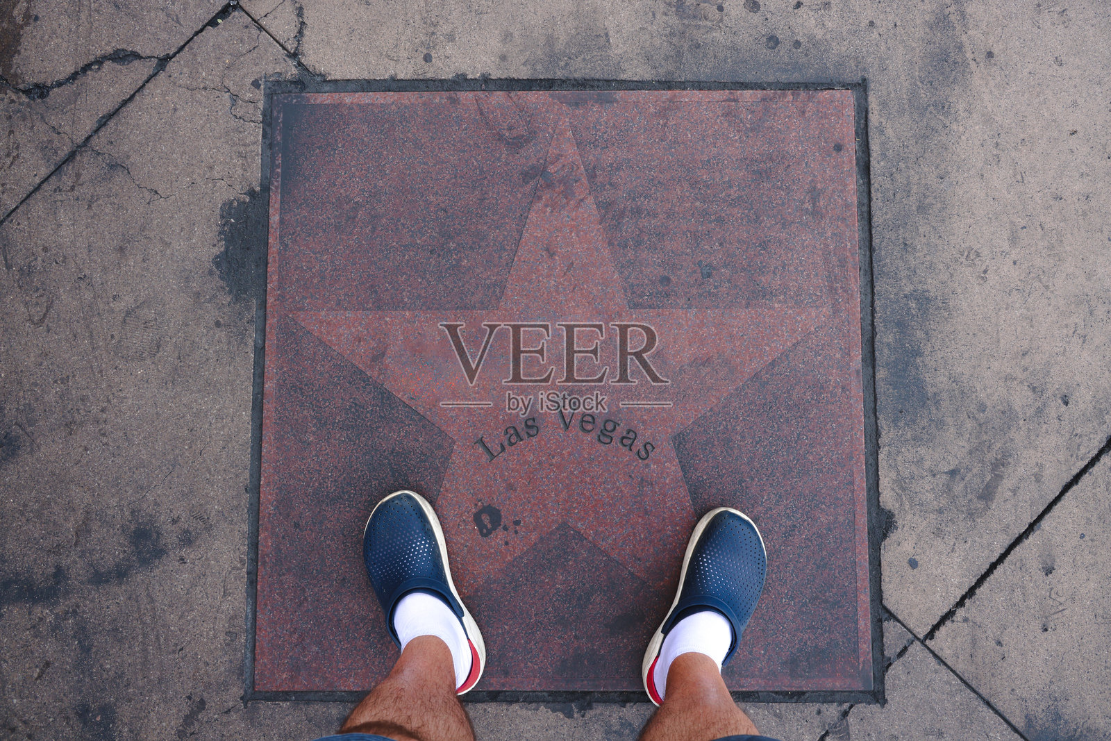 一位游客站在刻有拉斯维加斯字样的路边铭牌星星上，脚穿运动鞋。照片摄影图片