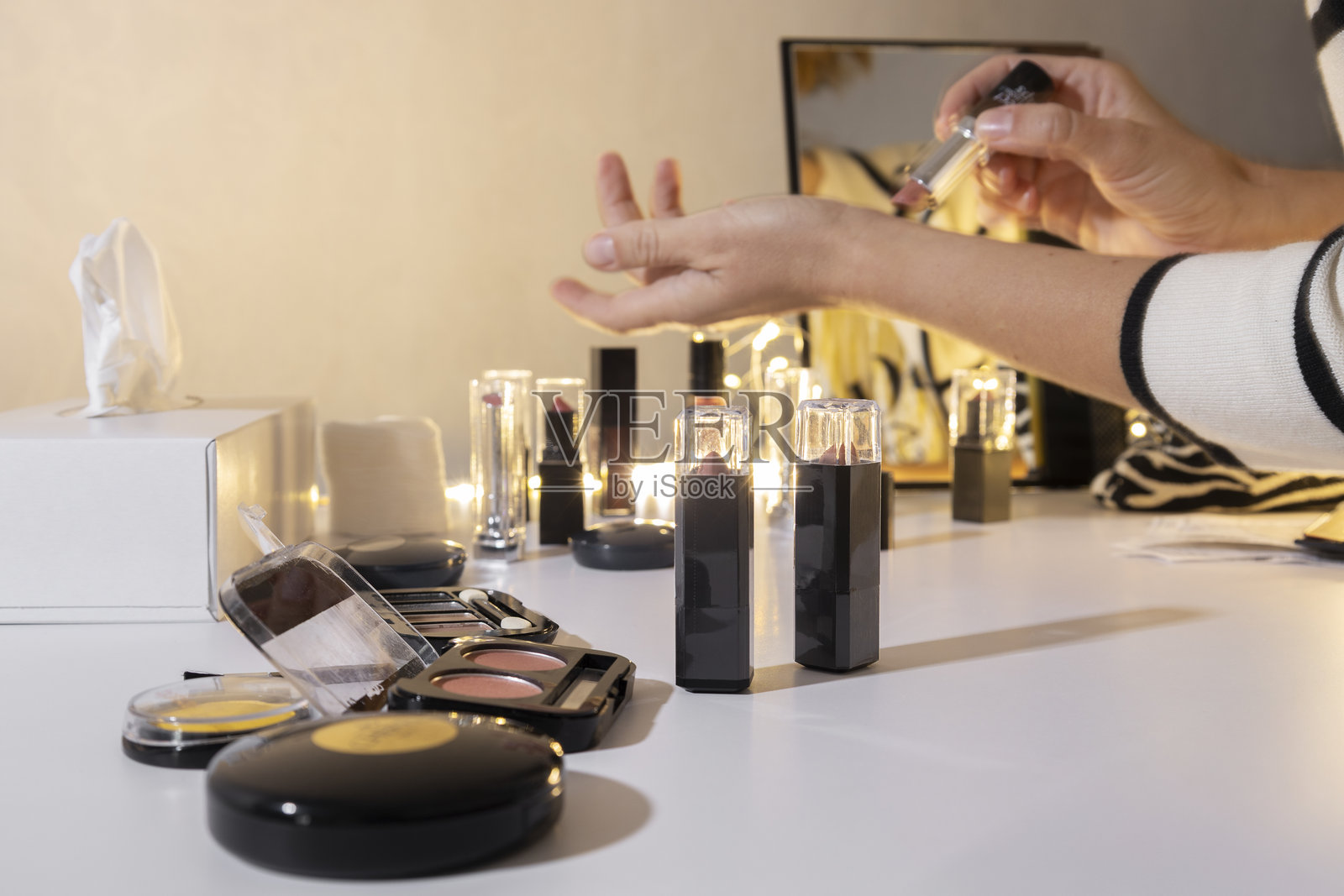 一位女士在美妆店的化妆品柜台附近，在手腕上试用柔和的粉色口红，以比较颜色并为她的服装挑选合适的口红。照片摄影图片