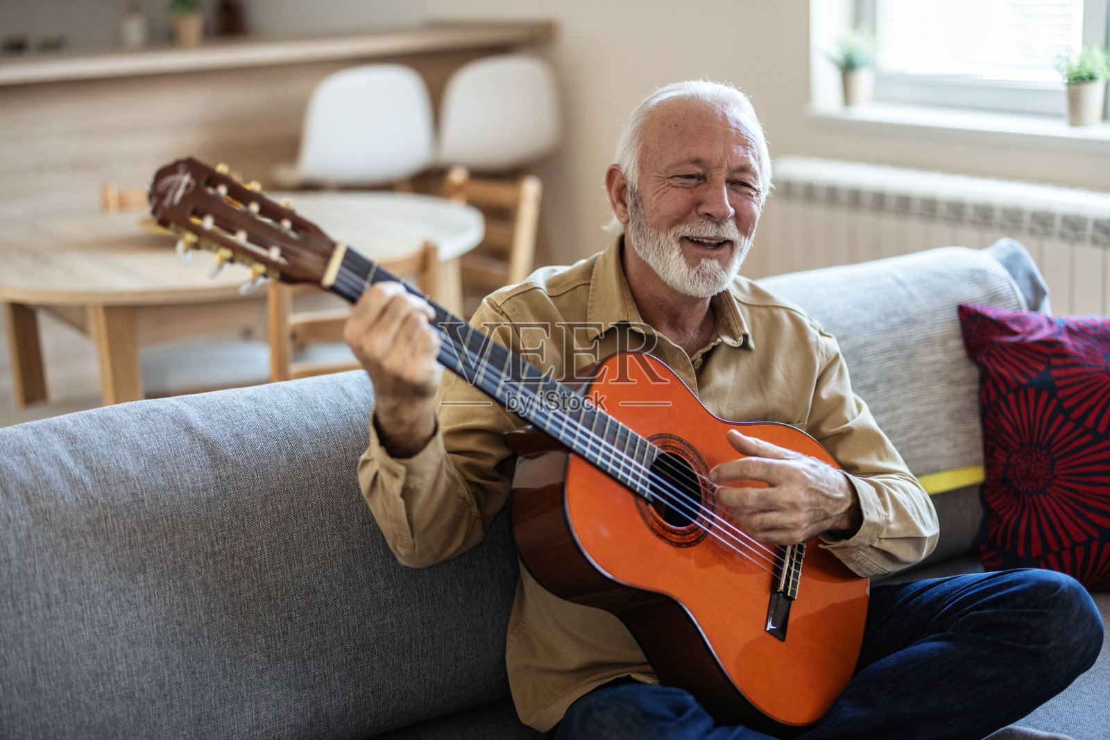 留胡子的老人弹奏原声乐器吉他。这位留胡子的老人正弹奏着他新创作的歌曲，是一位有创造力的音乐人。照片摄影图片