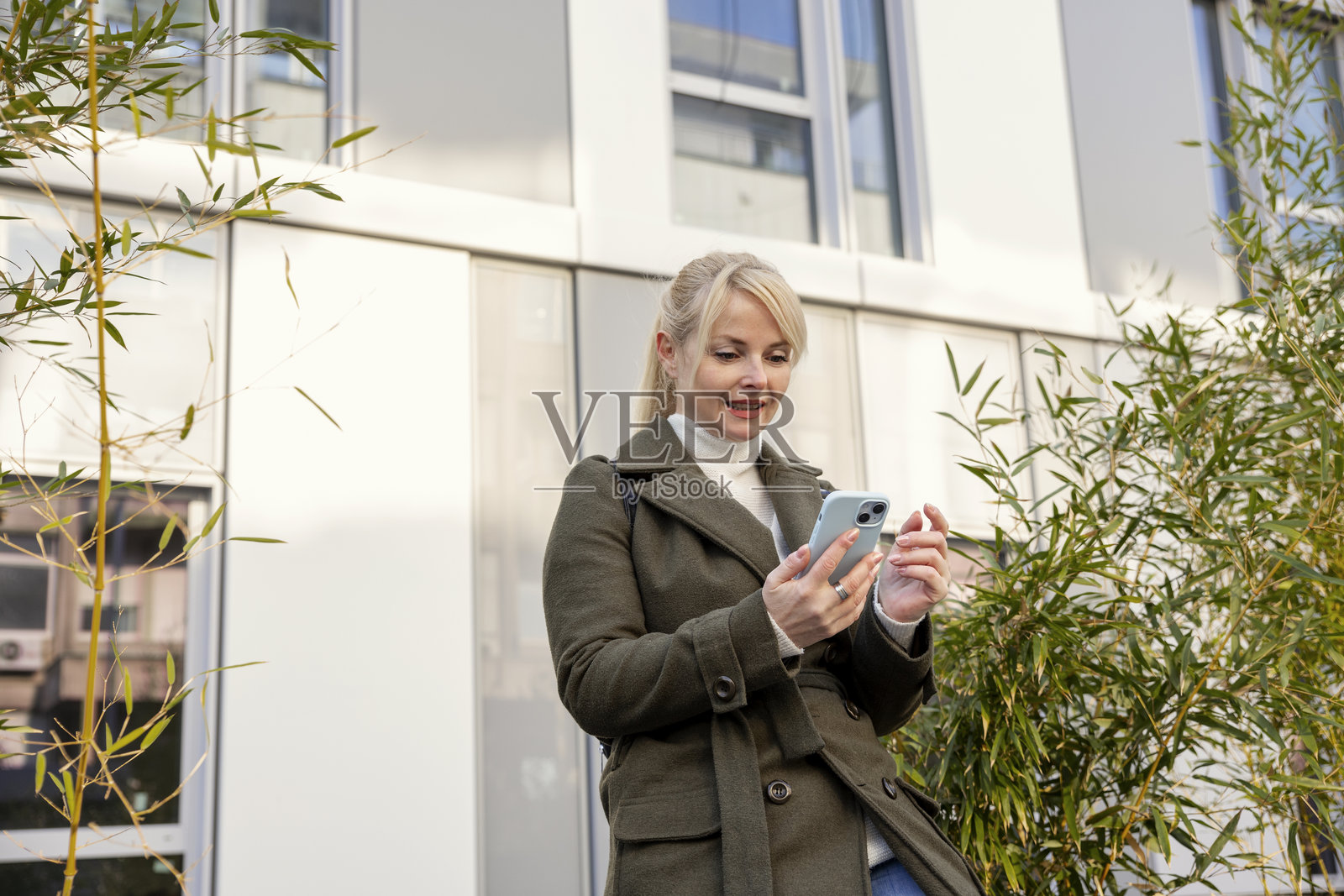 女人在城市背景下使用智能手机时面带微笑照片摄影图片