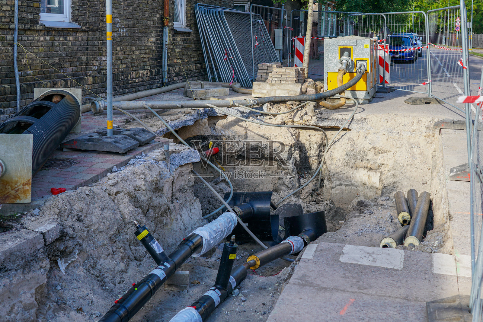 城市街道工地上，供暖管道更换期间，排水泵正在排干施工基坑。照片摄影图片