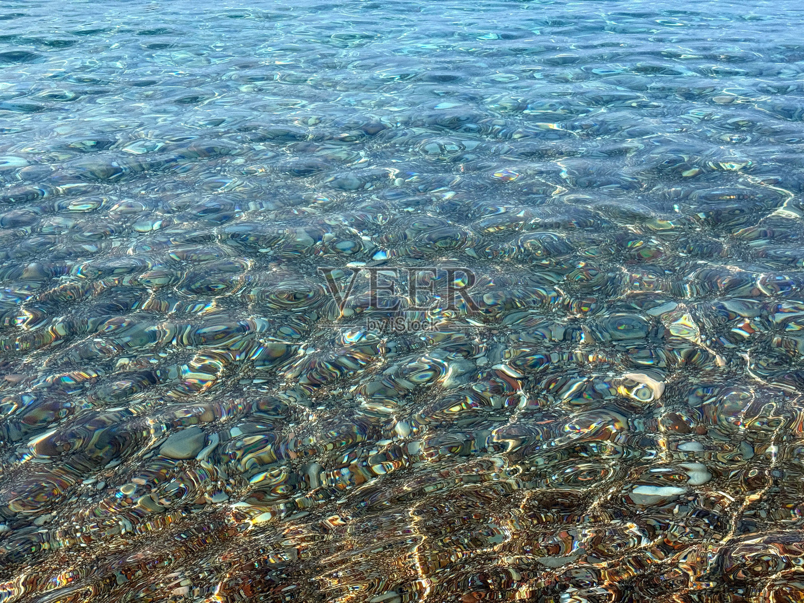 清澈的地中海中的鹅卵石和石块。照片摄影图片