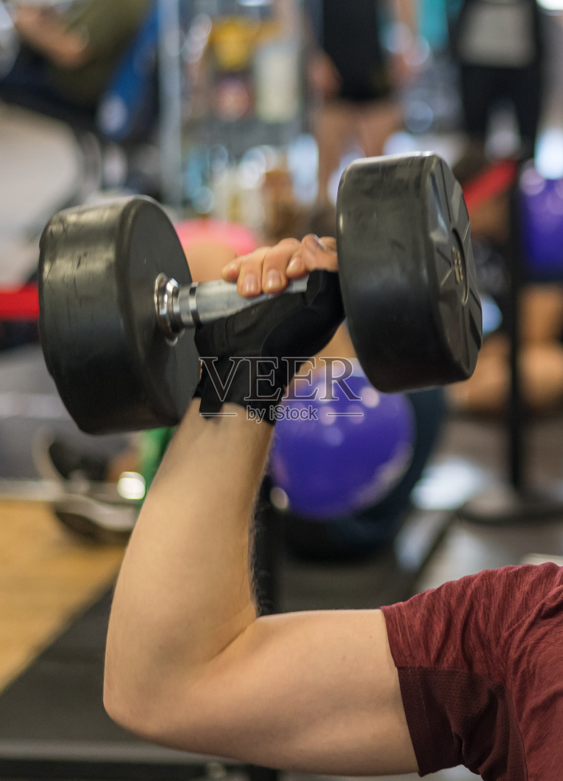一个人在健身房举着沉重的哑铃进行力量训练，展现了积极的生活方式和对健身的投入。照片摄影图片