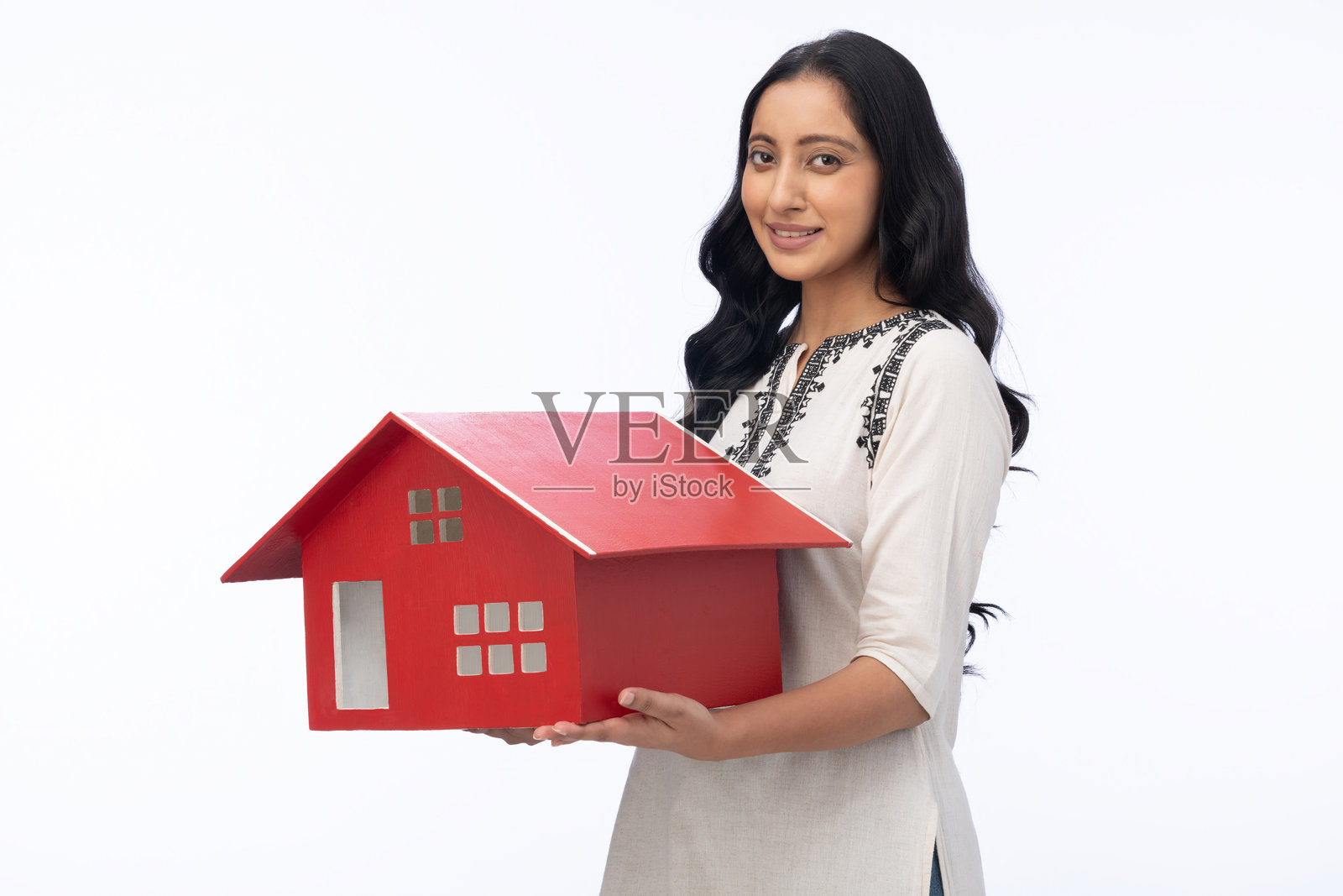 年轻女子身穿库尔塔，手持房屋模型，在白色背景下拍摄的照片素材照片摄影图片