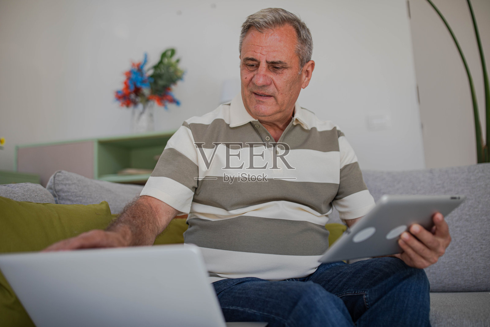 老年男子使用无线设备、笔记本电脑和平板电脑照片摄影图片