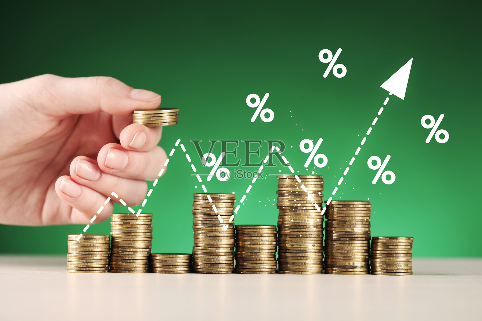 特写：女子在桌上叠硬币。上方有百分号和箭头。照片摄影图片