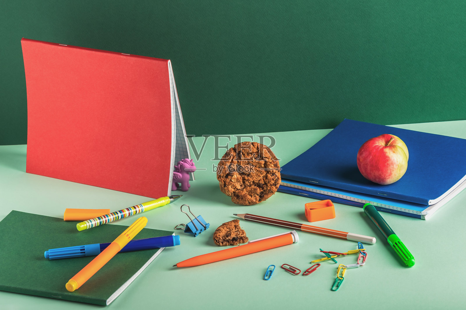 绿背景上的笔记本、铅笔、卷笔刀及其他文具和碎饼干构图。工作场所的组织。选择性聚焦。返校。\n\n**Translation Analysis:**\n- The phrase照片摄影图片