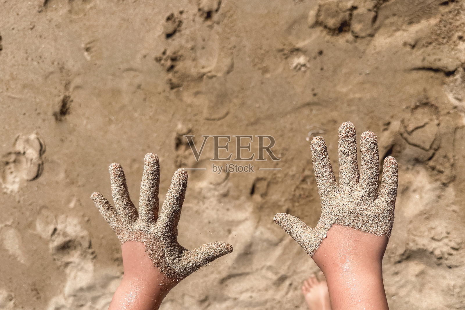 孩子们的小手在沙滩上，背景是沙质海滩。海滨度假。照片摄影图片