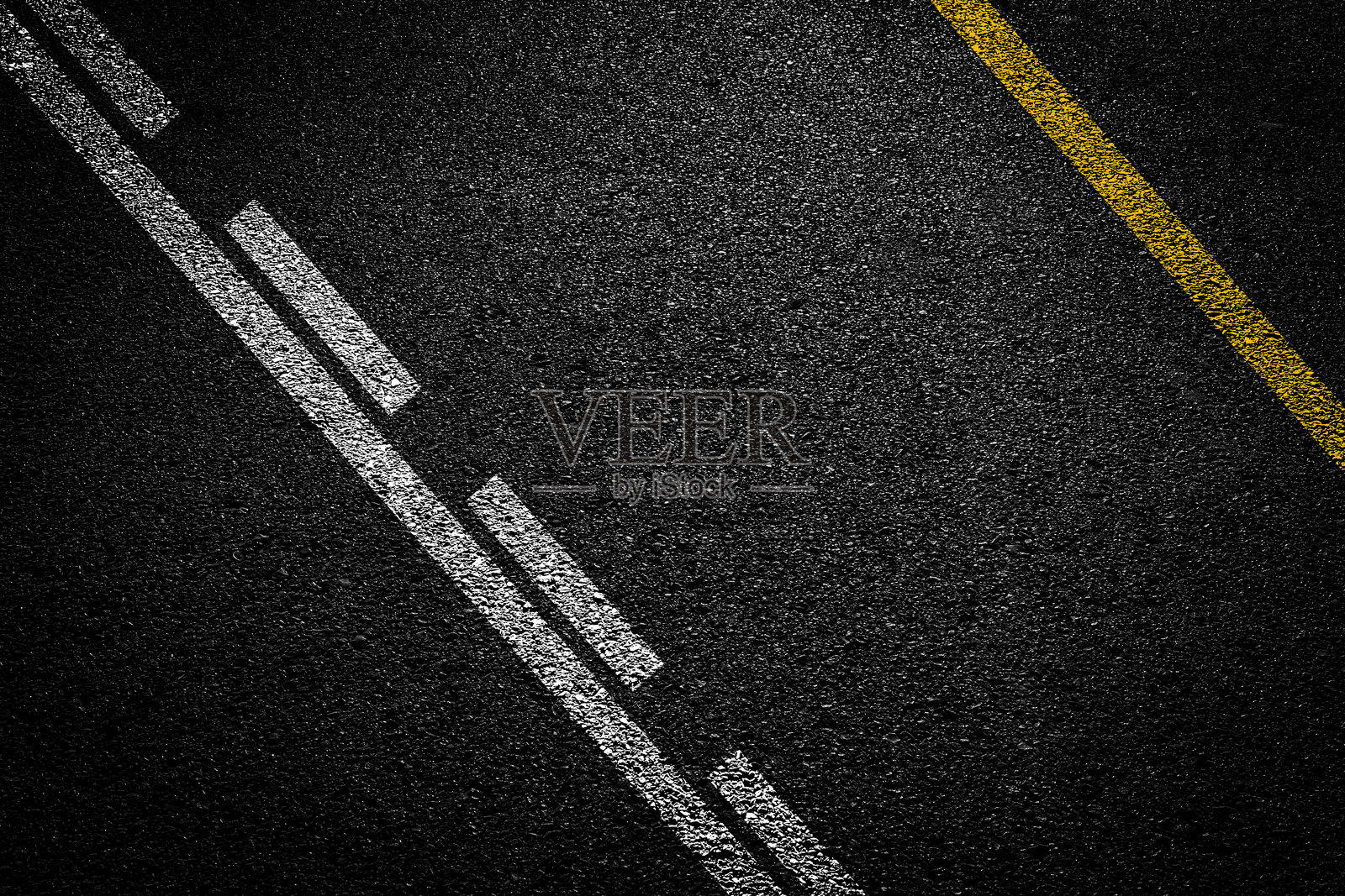 地表粗糙的沥青，带有黄色线条和细小石块的无缝深灰色柏油路面，纹理背景，俯视角度照片摄影图片