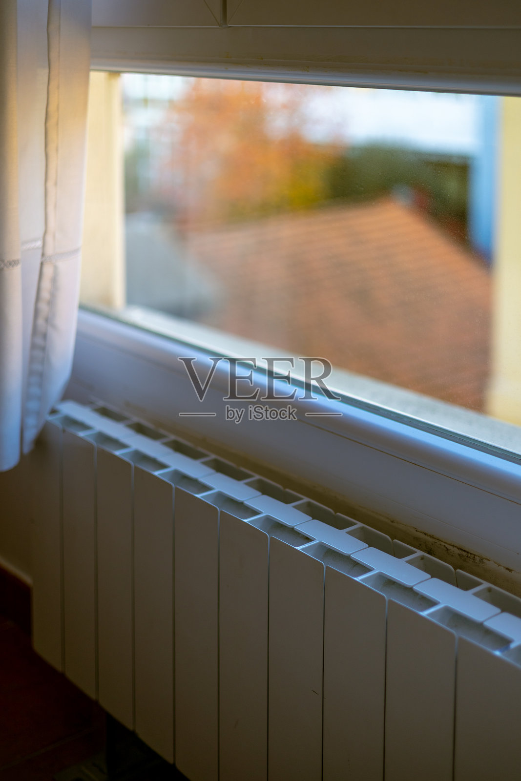 窗户下的白色中央供暖散热器，在寒冷的秋季温暖着舒适的家。体现居家舒适、能源成本和供暖季开始的概念。照片摄影图片