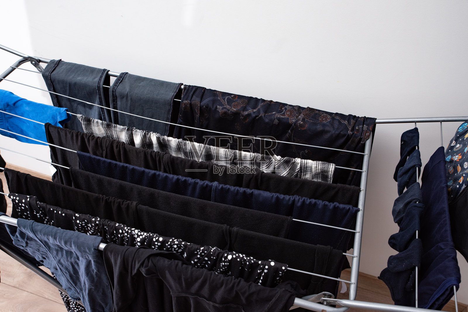 深色衣物在室内金属晾衣架上晾干。居家日常与清洁概念照片摄影图片